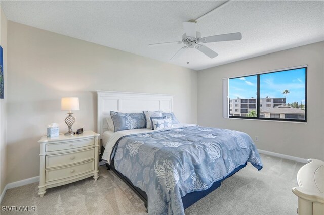 carpeted bedroom featuring ceiling fan and a textured ceiling