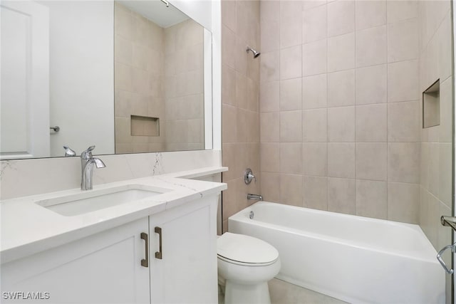 full bathroom featuring tiled shower / bath combo, vanity, and toilet