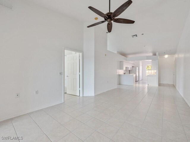 unfurnished living room with ceiling fan, light tile patterned floors, and high vaulted ceiling