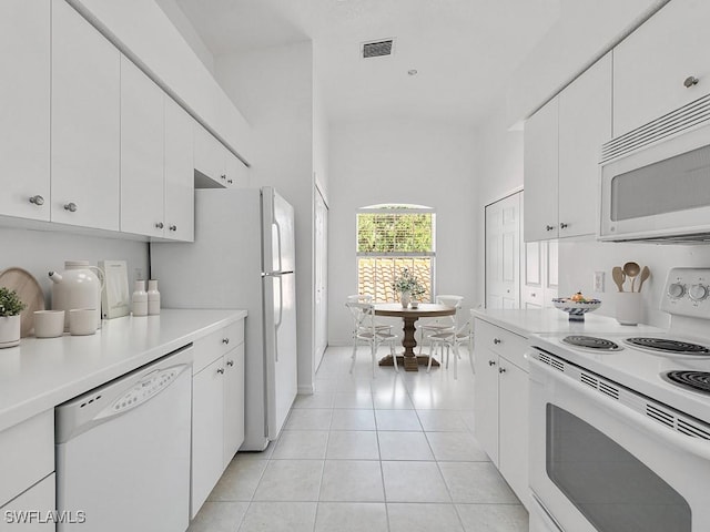 kitchen with white cabinetry, light tile patterned floors, and white appliances