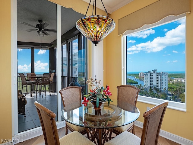 dining area featuring wood-type flooring, plenty of natural light, ornamental molding, and ceiling fan