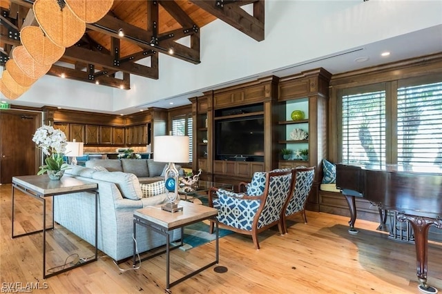 living room featuring beamed ceiling, light wood-type flooring, and high vaulted ceiling