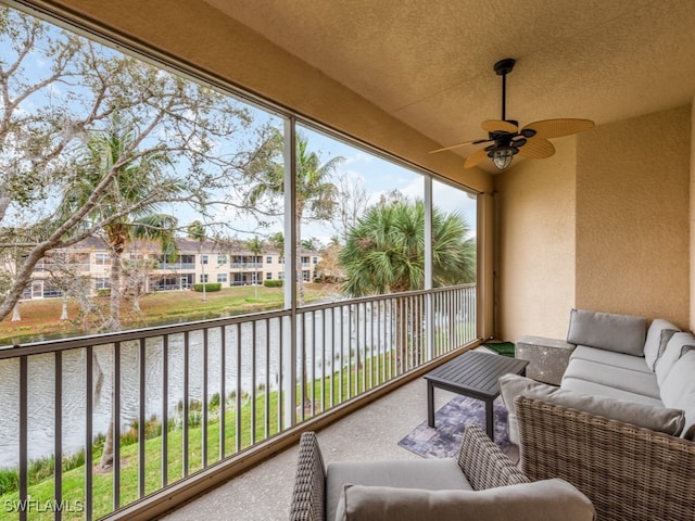 sunroom featuring a water view and ceiling fan