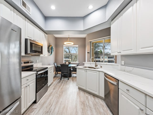 kitchen featuring pendant lighting, appliances with stainless steel finishes, sink, and white cabinetry