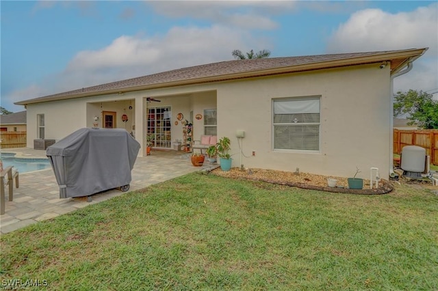 back of property featuring a lawn, a patio, and a fenced in pool