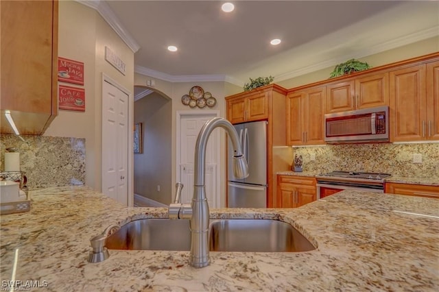 kitchen with sink, decorative backsplash, stainless steel appliances, crown molding, and light stone countertops