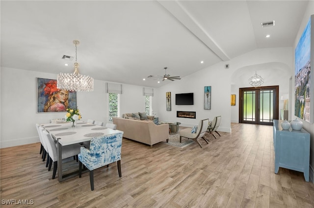 dining room with ceiling fan with notable chandelier, plenty of natural light, light hardwood / wood-style floors, and lofted ceiling with beams