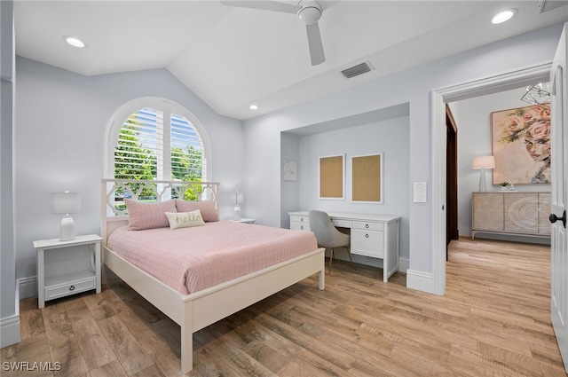 bedroom with ceiling fan, light wood-type flooring, built in desk, and vaulted ceiling