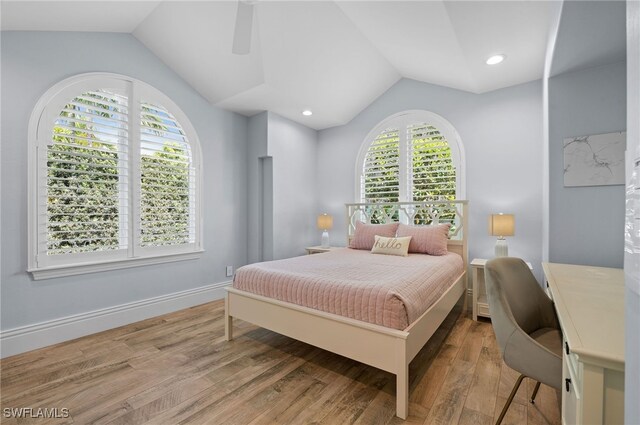 bedroom with hardwood / wood-style flooring, multiple windows, and lofted ceiling