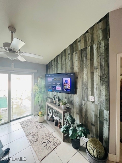 living room with wooden walls, tile patterned floors, vaulted ceiling, and ceiling fan