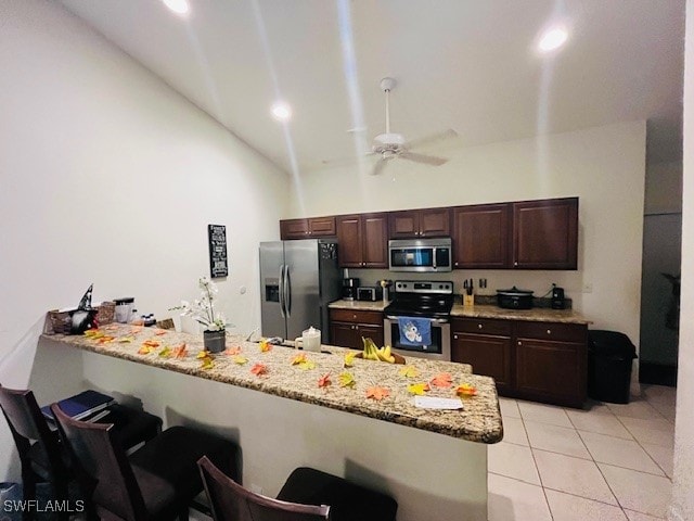 kitchen featuring kitchen peninsula, a breakfast bar area, ceiling fan, high vaulted ceiling, and stainless steel appliances