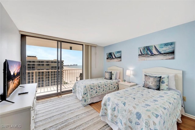 bedroom featuring baseboards, access to outside, floor to ceiling windows, and wood finished floors