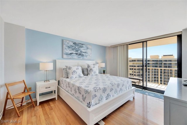 bedroom with light wood-style floors, access to outside, floor to ceiling windows, and baseboards