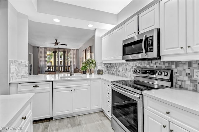 kitchen with ceiling fan, sink, backsplash, white cabinetry, and appliances with stainless steel finishes