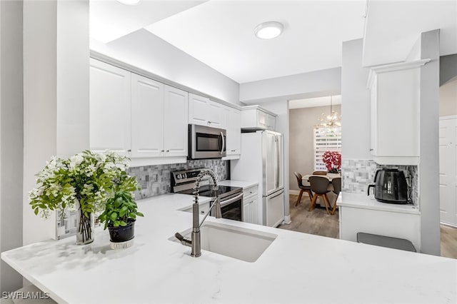 kitchen featuring a notable chandelier, stainless steel appliances, sink, and tasteful backsplash