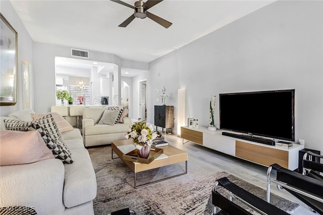 living room with ceiling fan with notable chandelier and hardwood / wood-style floors