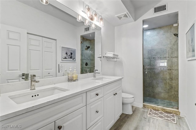 bathroom featuring hardwood / wood-style floors, a shower with shower door, vanity, and toilet