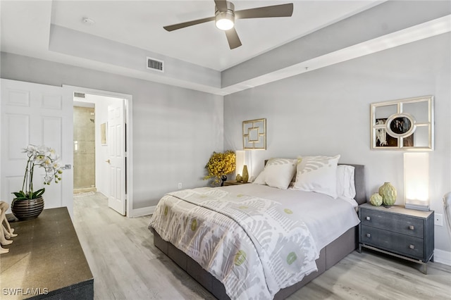 bedroom featuring light hardwood / wood-style flooring, connected bathroom, and ceiling fan