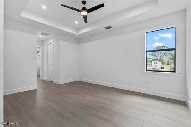 unfurnished room featuring a tray ceiling, ceiling fan, and hardwood / wood-style flooring