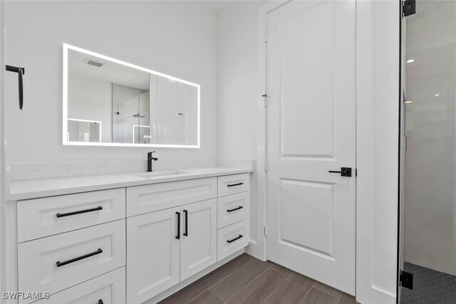 bathroom with vanity, hardwood / wood-style floors, and a shower with door