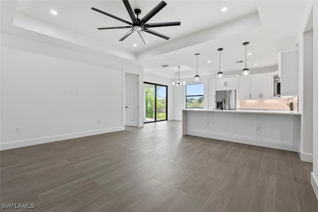 unfurnished living room featuring ceiling fan, a raised ceiling, hardwood / wood-style floors, and sink