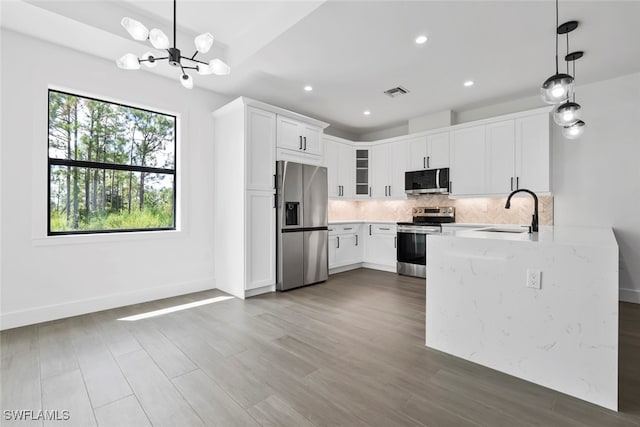 kitchen with white cabinets, sink, stainless steel appliances, and decorative light fixtures