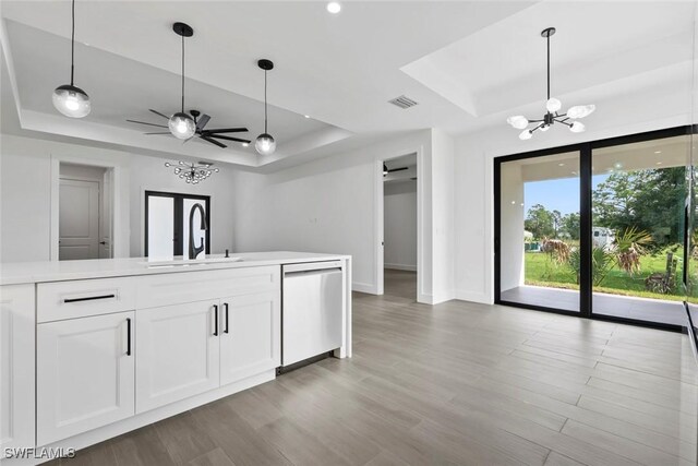 kitchen with sink, stainless steel dishwasher, white cabinetry, a tray ceiling, and ceiling fan with notable chandelier