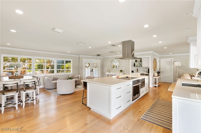 kitchen with island exhaust hood, white cabinetry, light hardwood / wood-style flooring, and oven