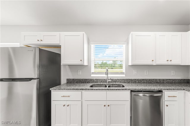 kitchen with dark stone counters, sink, white cabinets, and stainless steel appliances