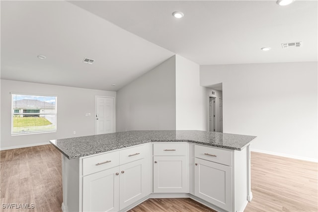 kitchen featuring white cabinets, vaulted ceiling, and light wood-type flooring