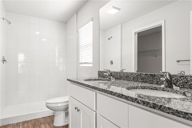 bathroom featuring tiled shower, hardwood / wood-style floors, vanity, and toilet