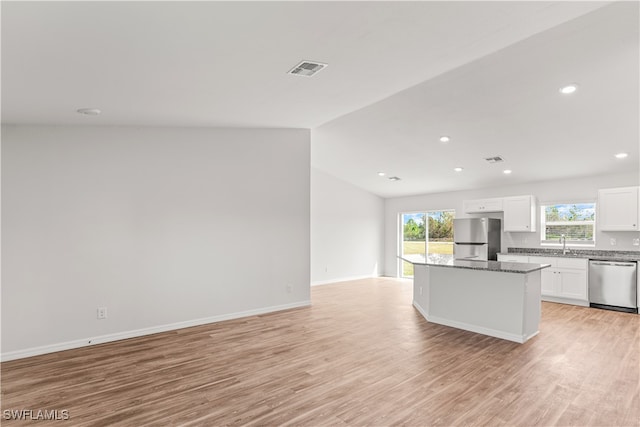 kitchen with plenty of natural light, white cabinetry, stainless steel appliances, and vaulted ceiling