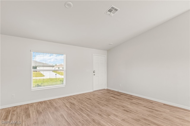 empty room with light hardwood / wood-style floors and lofted ceiling