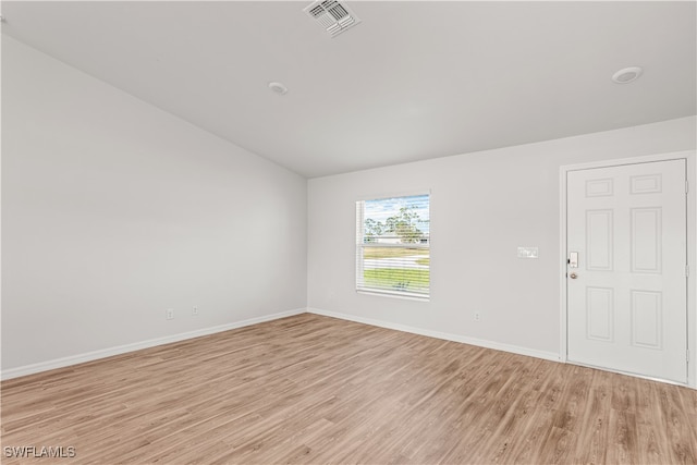 spare room with vaulted ceiling and light hardwood / wood-style flooring