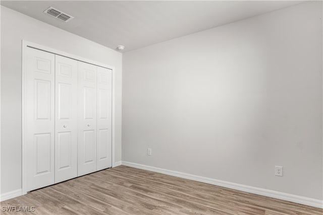 unfurnished bedroom with light wood-type flooring and a closet