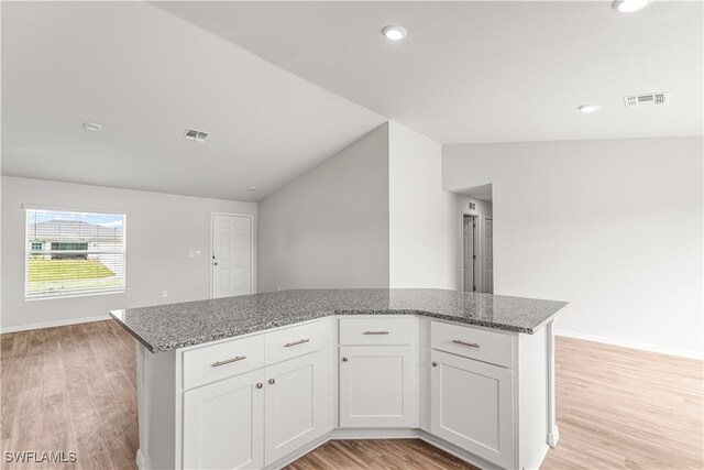 kitchen with white cabinets, light hardwood / wood-style floors, and vaulted ceiling