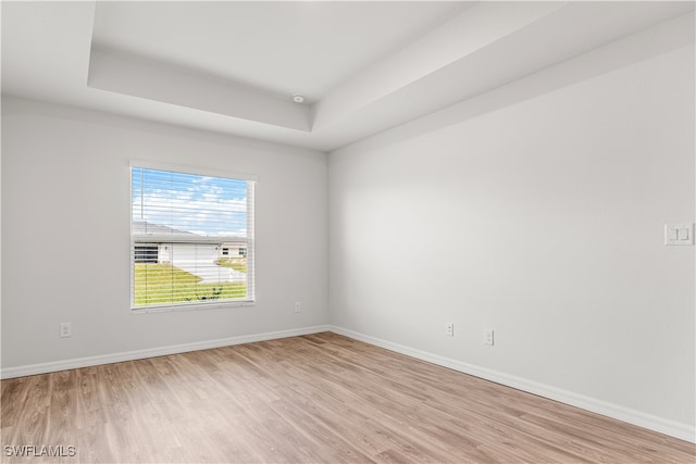 unfurnished room with a tray ceiling and light hardwood / wood-style floors