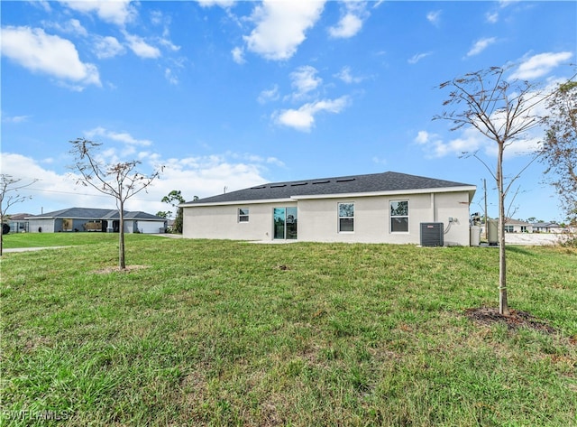 rear view of property featuring a lawn and central AC