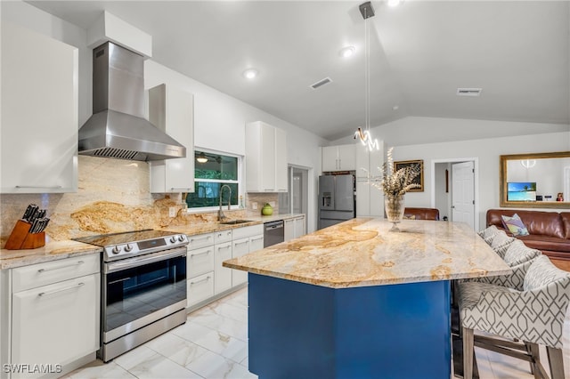 kitchen featuring vaulted ceiling, white cabinets, stainless steel appliances, sink, and wall chimney range hood