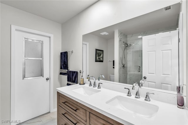 bathroom featuring a shower with shower door, vanity, and toilet