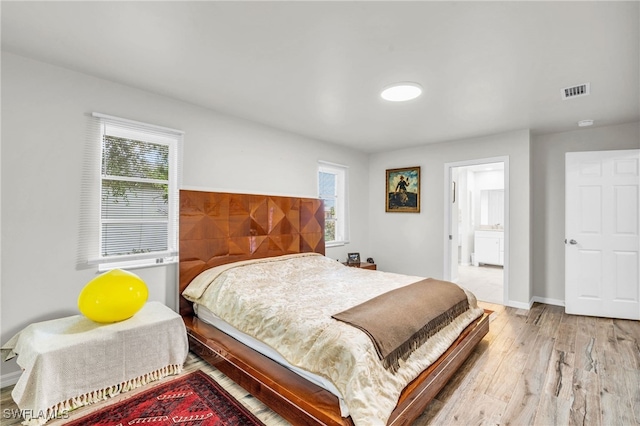 bedroom with light hardwood / wood-style floors and ensuite bath