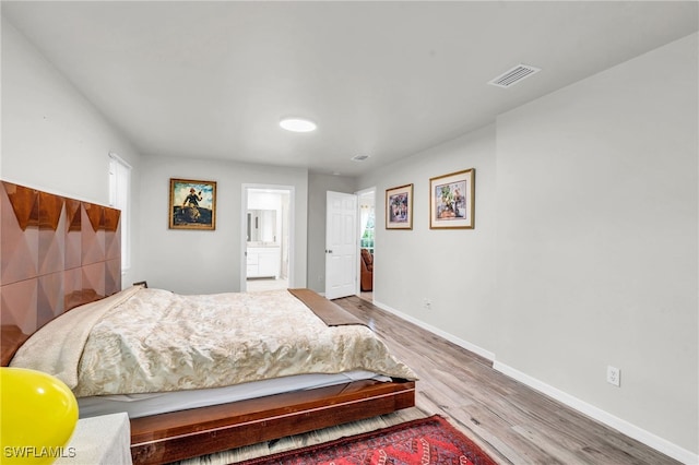 bedroom with light wood-type flooring and ensuite bath