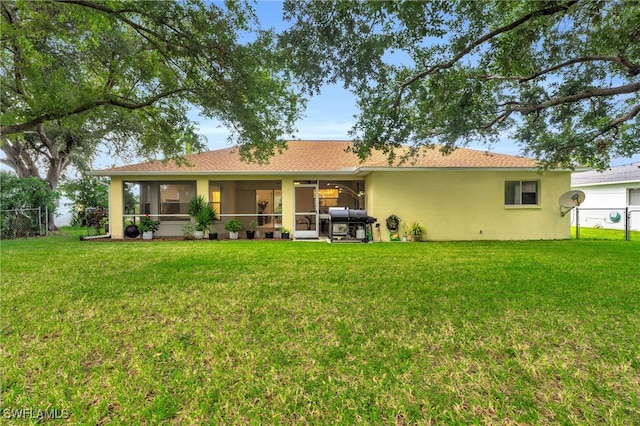 back of property featuring a lawn, a sunroom, and a patio