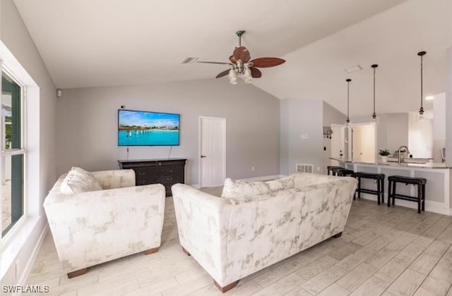 living room with ceiling fan, light hardwood / wood-style flooring, and vaulted ceiling