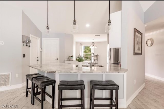 kitchen featuring light stone counters, decorative light fixtures, sink, and lofted ceiling