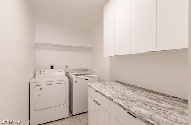 laundry room with cabinets, light hardwood / wood-style flooring, and washer and dryer