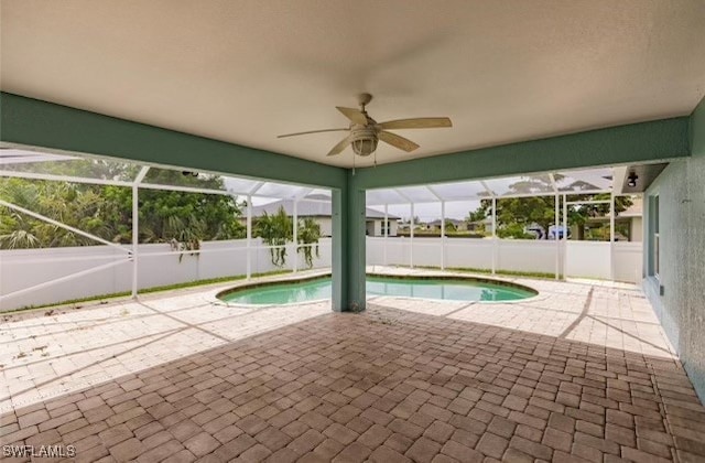 view of swimming pool featuring ceiling fan, glass enclosure, and a patio