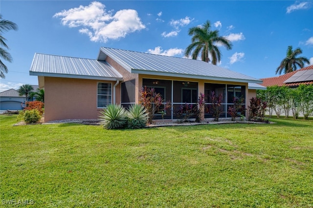 rear view of property featuring a yard and a sunroom