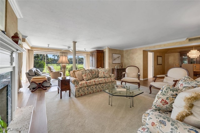 living room featuring light hardwood / wood-style floors, ceiling fan with notable chandelier, a fireplace, and crown molding