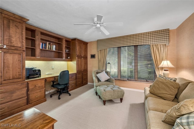 office featuring ceiling fan, light colored carpet, and built in desk